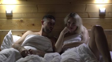 Akşamları yatakta genç seksi bir çift. Erkek ve kadın, heyecanlı evli çift yatak odasında. Evli bir çift yetişkinler için erotik bir televizyon izliyor..