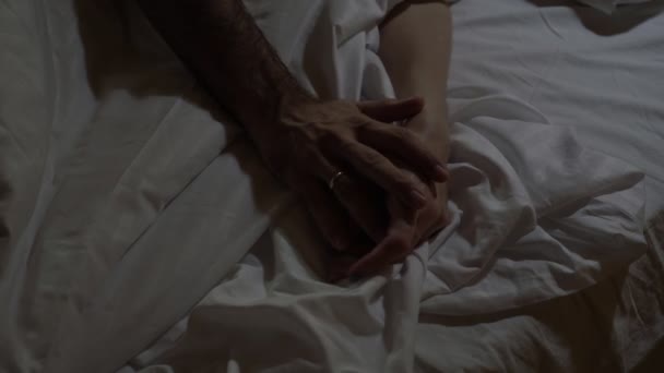 Male and female hand on the bed. Young married couple sleeping on the bed, hands close-up. Love and happy family concept — Stock Video