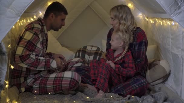Ευτυχισμένη οικογένεια με πιτζάμες γιορτάζει Χριστούγεννα. Οικογένεια με ένα παιδί στο χριστουγεννιάτικο σπίτι — Αρχείο Βίντεο