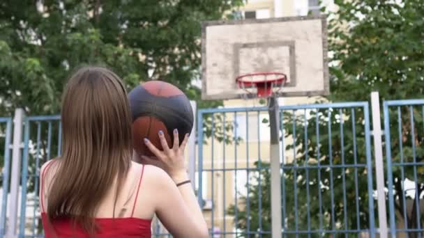 Mujer joven marca un gol en el aro de baloncesto. El atleta golpea la pelota en una canasta de baloncesto, cámara lenta — Vídeo de stock