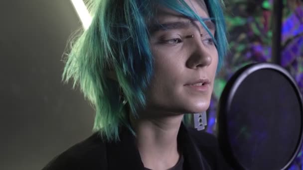 Jeune homme séduisant aux cheveux bleus chante dans un microphone dans un studio d'enregistrement — Video