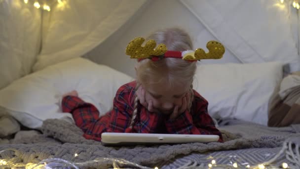 Świąteczny nastrój, dziewczynka z tabletem w domu. Dziecko czeka na Nowy Rok. — Wideo stockowe