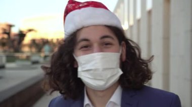 Tıbbi maskeli ve Noel Baba şapkalı bir adam. Coronavirus sırasında yeni yıl ya da Noel.
