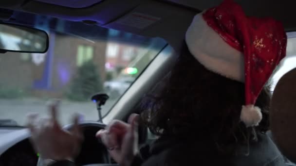 Noel, Noel Baba şapkalı mutlu adam arabada. Bir adam araba sürerken Noel Baba şapkasıyla dans ediyor. — Stok video