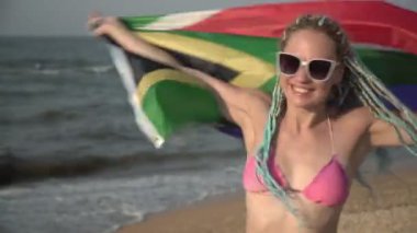 Deniz kenarında Güney Afrika bayrağı taşıyan güzel, mutlu bir kadın. Güney Afrika 'da plaj tatili