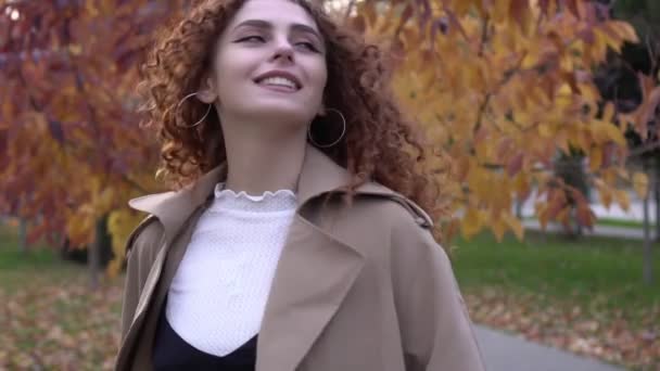 Schöne glückliche Frau im Regenmantel spaziert im herbstlichen Park, Zeitlupe — Stockvideo