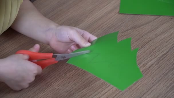 Un enfant coupe un sapin de Noël dans du papier. Noël et Nouvel An en famille concept — Video
