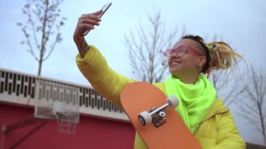 Modern bir kadın açık havada akıllı telefondan selfie çekiyor. Modern gençlik yaşam tarzı kavramı