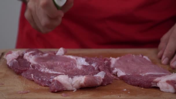 Un uomo picchia la carne con un martello in cucina. Un uomo prepara una braciola di maiale, al rallentatore. Un pezzo di carne viene battuto con un martello da cucina — Video Stock