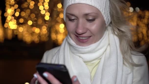 Noël, femme heureuse regarde dans un smartphone à l'extérieur. Miracle de Noël et ambiance festive — Video