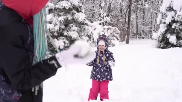 Dziecko z rodzicami grającymi w kulki śniegu. Mama i córka rzucają śnieżkami w zimowym parku lub lesie — Wideo stockowe