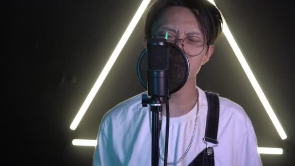 Jonge moderne Aziatische zanger in opnamestudio. Een man zingt in een microfoon — Stockvideo