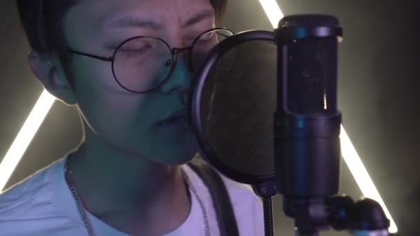 Jong aantrekkelijk aziatisch man zingt in een microfoon in een opname studio — Stockvideo