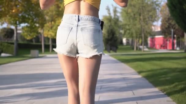 Молодая сексуальная женщина в шортах гуляет по парку. Портрет сексуальной студентки на открытом воздухе — стоковое видео
