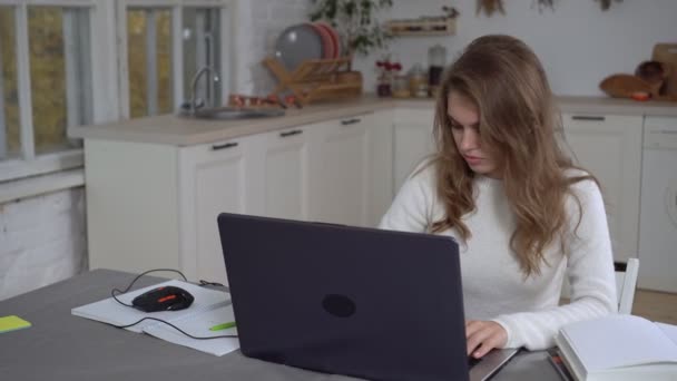 Ung kvinna med laptop arbetar hemma. Attraktiv kvinnlig student med bärbar dator studerar på distans hemma — Stockvideo