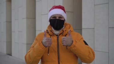 Noel, tıbbi maskeli bir adam onaylıyor. Bir adam yeni yılı koruyucu bir maskeyle kutlar.