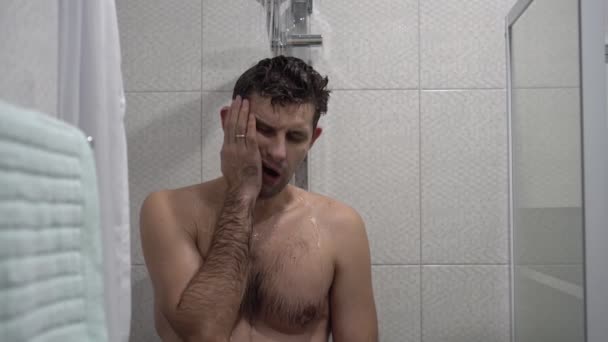 Śpiący mężczyzna myje się pod prysznicem. Zmęczony człowiek stoi pod prysznicem i próbuje się obudzić. Poranne przebudzenie — Wideo stockowe