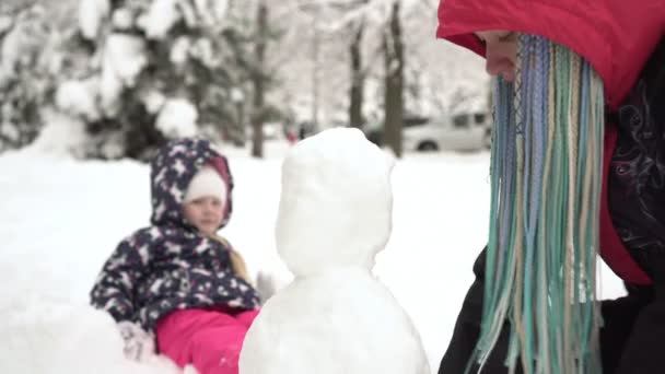 Famille fait un bonhomme de neige dans le parc. Un enfant avec maman faire une figure de neige dans la rue — Video