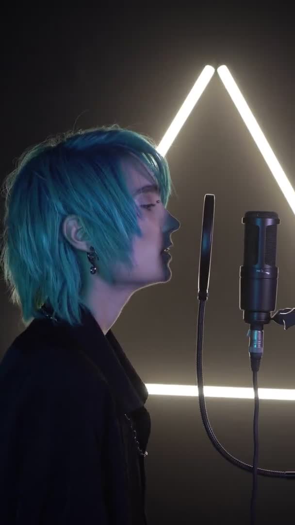 Vertical video: a singer with blue hair sings into a microphone in a professional recording studio. Modern singer. — Stock Video