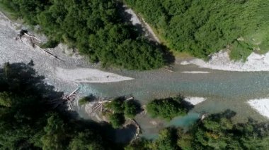 Dağ saydam nehir ve yeşil orman. Kurumuş ağaçlar nehir yatağında yatıyor, Nehrin yukarısından görünüyor.