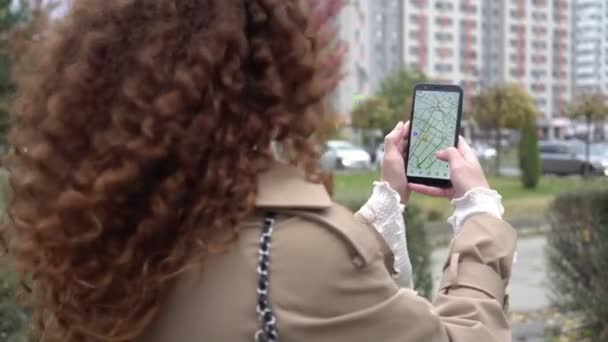 Γυναίκα σε εξωτερικούς χώρους κρατώντας smartphone με χάρτη της πόλης. Ένα χέρι πρόσωπο κατέχει ένα smartphone με μια εφαρμογή σε απευθείας σύνδεση χάρτες. Έννοια GPS και οδηγός ταξιδιού στο διαδίκτυο. — Αρχείο Βίντεο