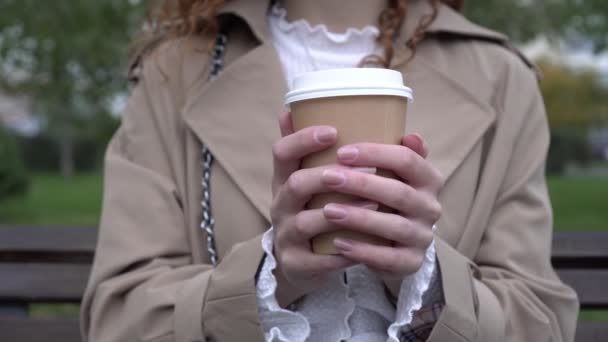 En kvinde holder en papirkop med takeaway kaffe. Efterår, kvinde udendørs drikker kaffe eller te til at gå Videoklip