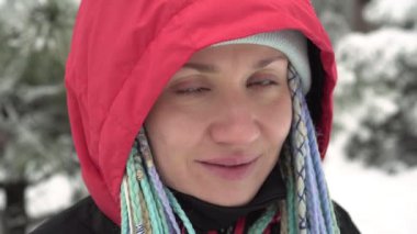 Kışın dışarıda mutlu bir kadın. Kar arka planında gülümseyen genç bir kadın, yakın plan. Etkin kış konsepti