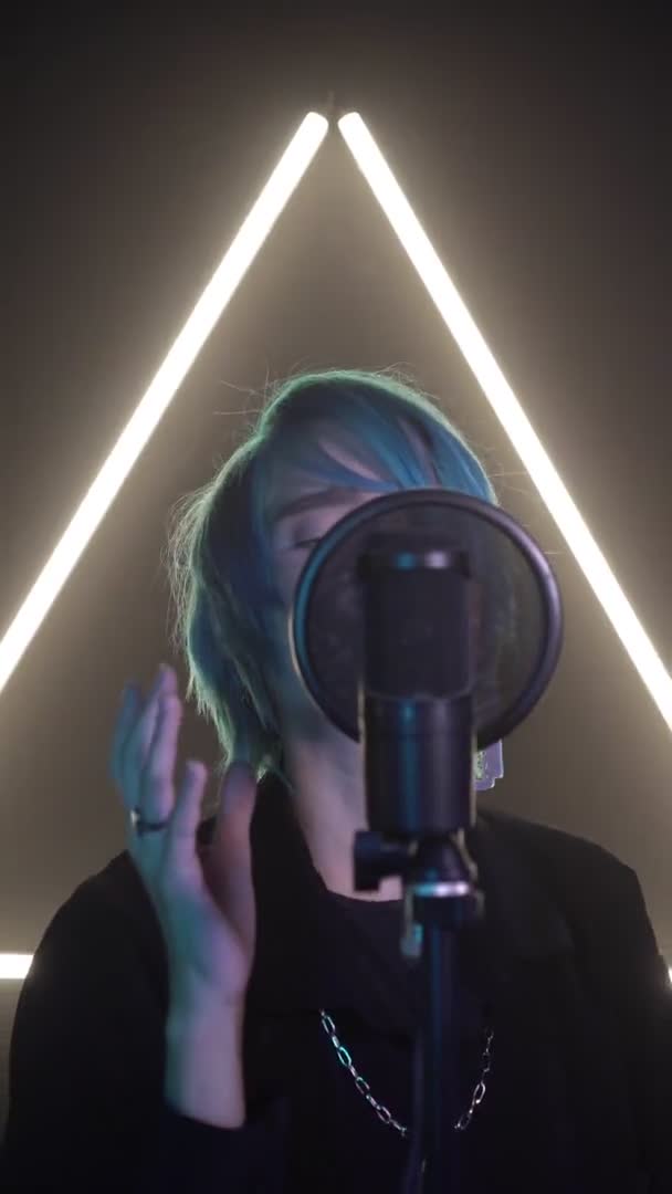 垂直录像：一个蓝发歌手在专业录音室对着麦克风唱歌。一个现代的年轻歌手在排练一首歌 — 图库视频影像