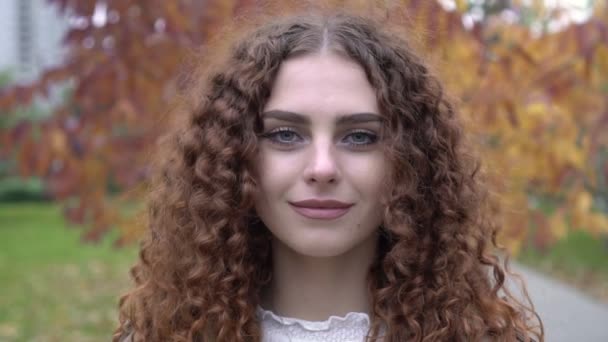 Portret młodej kobiety z brązowymi włosami i zielonymi oczami na jesiennym tle. Piękna kobieta w jesiennym parku — Wideo stockowe