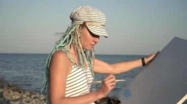 Modern kadın ressam deniz kenarında resim yapıyor. Ressam açık havada bir resim çiziyor.