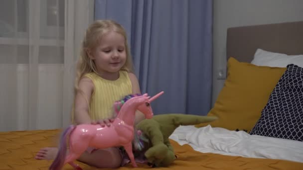 Niña jugando con juguetes en casa. Una chica está jugando con un unicornio en la habitación — Vídeos de Stock