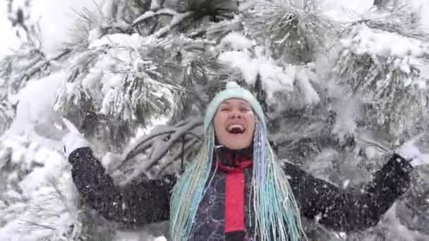 Śnieg spada z drzewa na szczęśliwą kobietę. Młoda pozytywna kobieta raduje się zimą i śniegiem w przyrodzie — Wideo stockowe