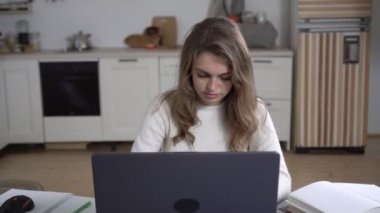 Genç bir kadın evde dizüstü bilgisayarla çalışıyor. Bir salgın sırasında uzaklık öğrenme veya çalışma kavramı