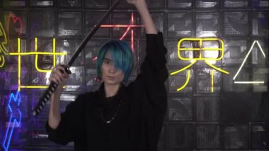 Genç bir adam ya da kadın Japon bir katana kılıcı tutuyor. Modern Samuray. Japonca arkaplanda yazılan- karanlıktan aydınlığa izin ver