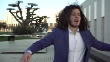 Genç mutlu iş adamı sevinir ve dans eder. Dışarıda bir adam dans ediyor. Neşeli bir iş adamının portresi