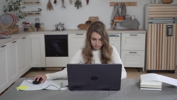 Vrouwelijke studente met laptop en boeken die thuis studeren. De student bereidt zich voor op het examen. Een persoon bestudeert informatie met een laptop Stockvideo's