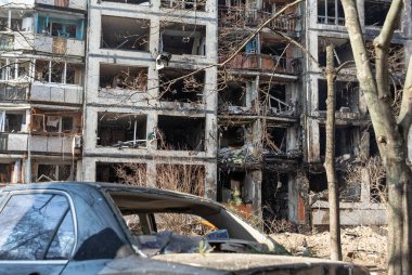 Bombardımandan sonra Kyiv 'deki yıkık dökük bir binanın arka planına çarpan bozuk bir araba. Rusya 'nın Ukrayna' ya saldırısı