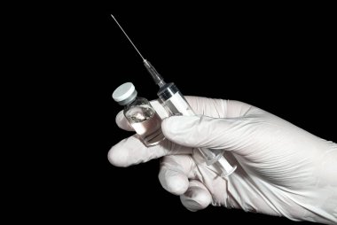 Hand in rubber glove holding a vial with medication and syringe. Medical equipment and medication