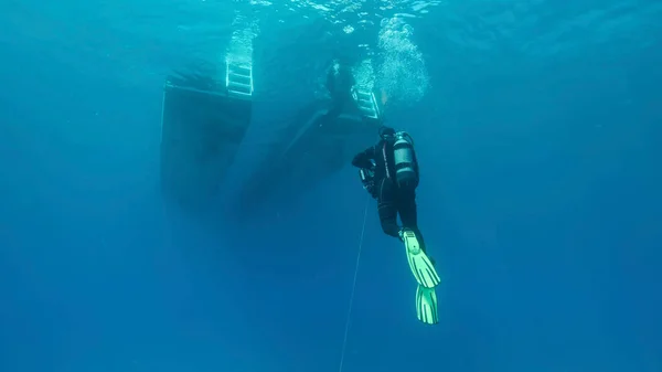 Scuba diver swim towards diving boat in blue water. Mediterranean Sea, Cyprus