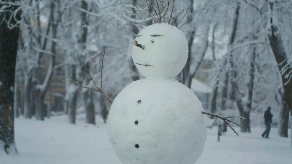 Happy funny snowman, on background of a strong snowfall.