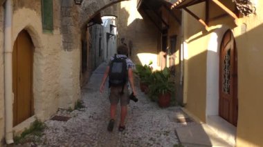 Kameralı bir adam Old Town caddesinde yürüyor. Rodos, Yunanistan.