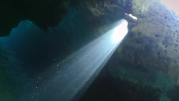 Šnorchlování, potápění: kamera se pohybuje k otvoru ve stropě jeskyně, kterým sluneční paprsky pronikají. — Stock video