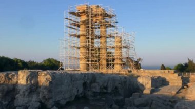 Batan güneşin ışınlarında yeniden inşa edilmiş Antik Yunan tapınağının sütunları. Rodos, Yunanistan.