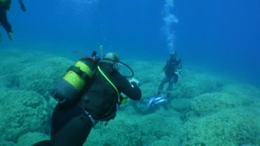 Dalış eğitimi: bir kız eğitmen dalış merkezi bir çift öğrenciyle ilk dalışı yapar.