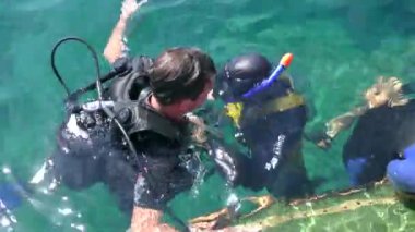 After dive, the dive center staff helps the student diver take off the air cylinder.