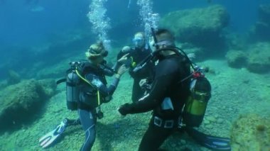 Diving training: a girl instructor diving center conducts the first dive with a pair of students, medium shot.