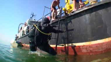 Dalgıç merdivenden gemiye doğru tırmanıyor, alttan bakıyor..