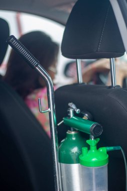 Tanque de oxigeno medico on la parte trasera del auto con mujer manejando