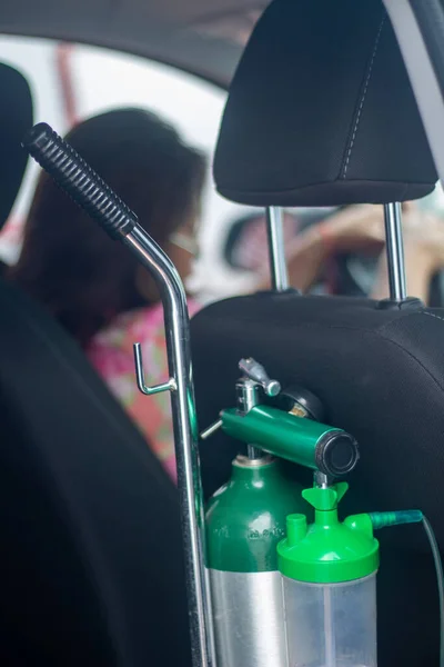 Tanque de oxigeno medico on la parte trasera del auto con mujer manejando