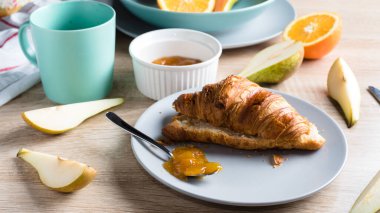 Sağlıklı kahvaltı. Kruvasan, çörek, kahve, reçel, meyve: portakal ve armut.. 